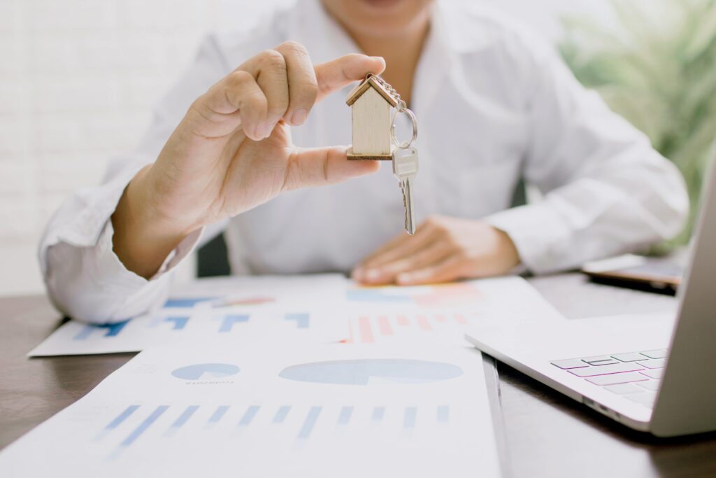 A financial advisor holds up housekeys over a desk covered in title insurance paperwork.
