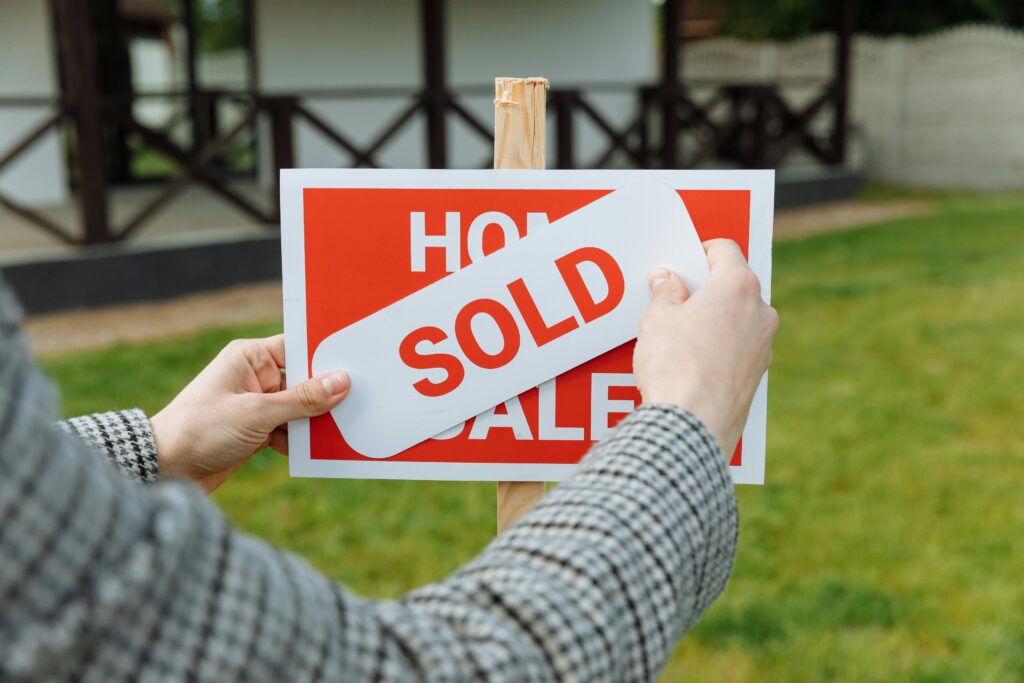 A real estate sign is changed to "sold" after buyer and seller finalized negotiations.